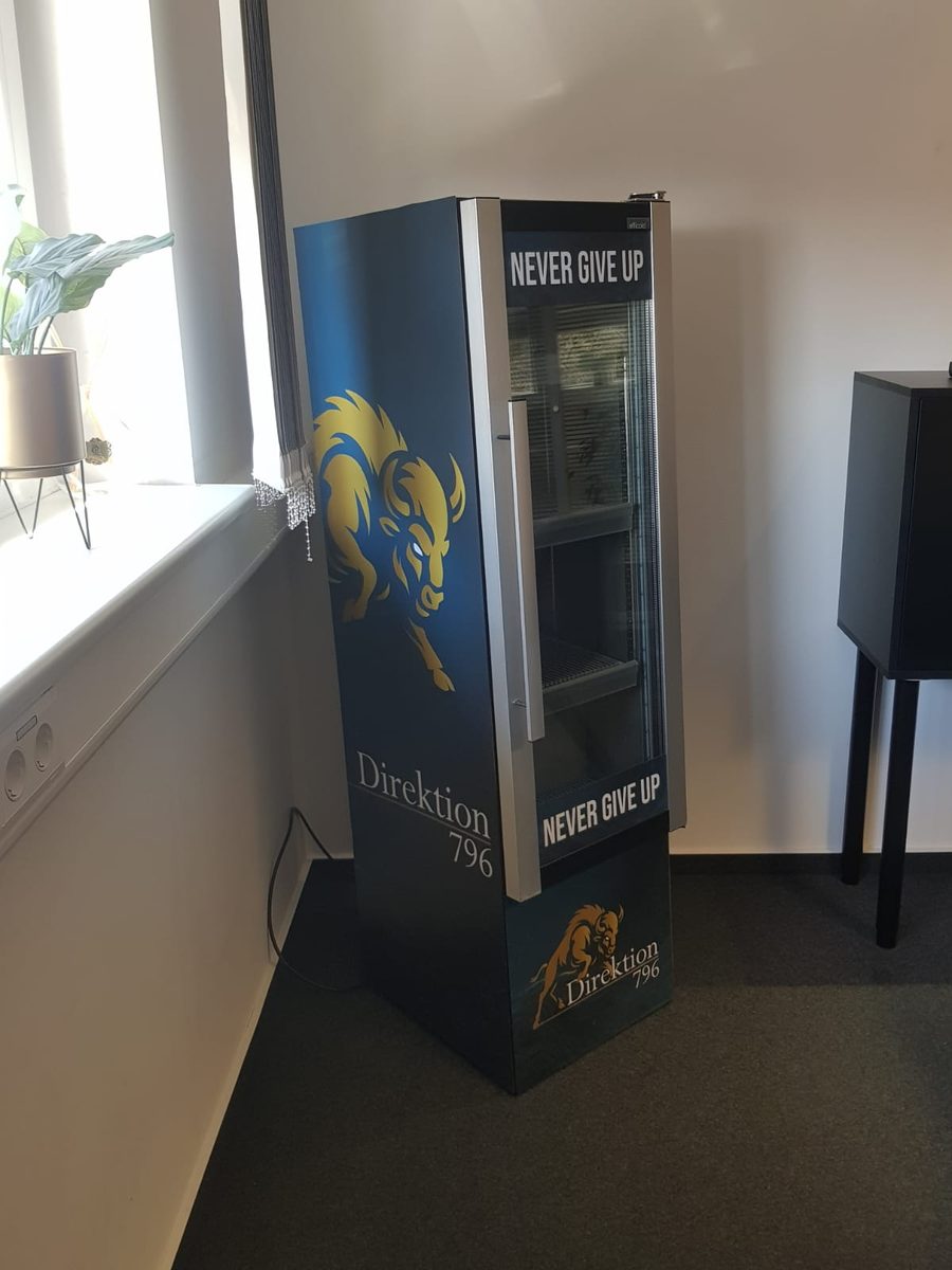 Vollflächig folierter Getränkekühlschrank Direktion 796 mit goldenem Bison-Logo und Schriftzug Never give up, als Objektbeklebung umgesetzt von twCREATIVO