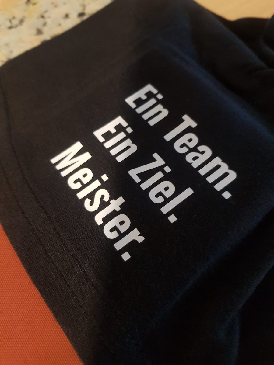 Schwarzes Teamshirt mit weißem Druck Ein Team Ein Ziel Meister, Textildruck von twCREATIVO